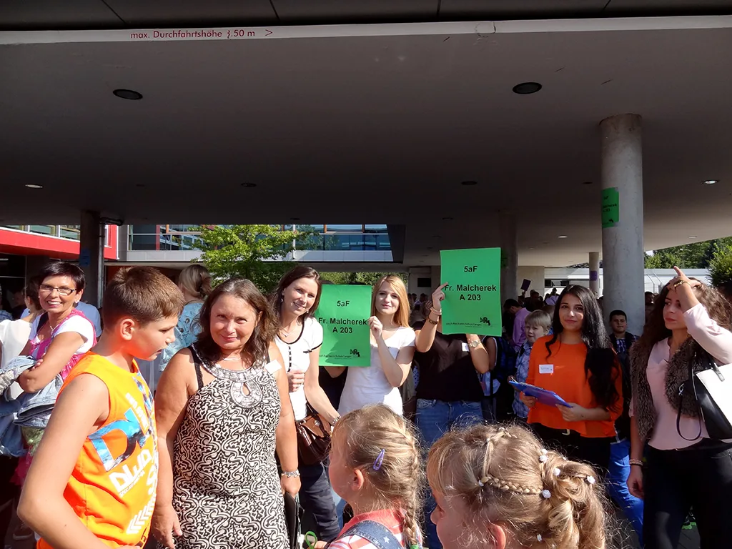 Kinder und Erwachsene mit grünen Klassenschildern.